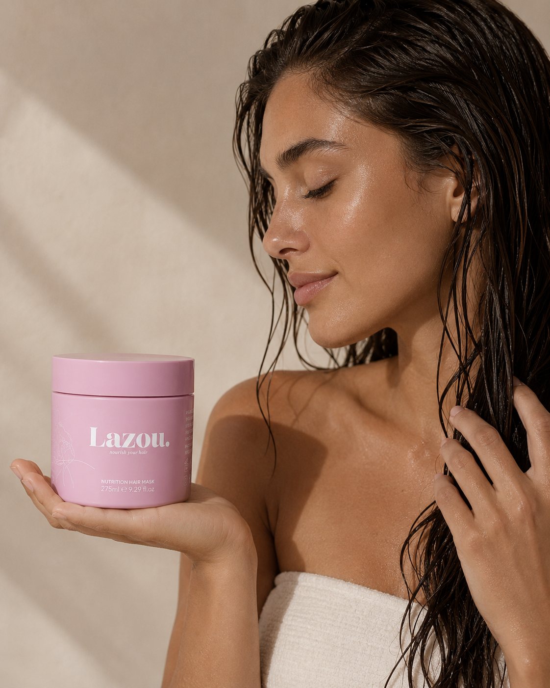 Woman with damp hair holding a pink jar labeled 'Lazou' against a beige background